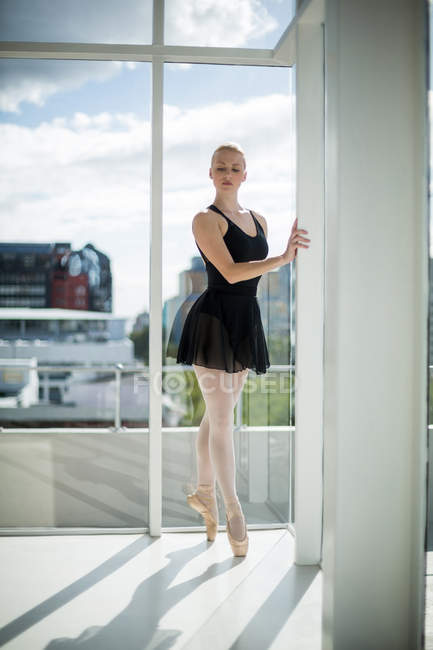 Балерина растягивается на стене во время репетиции балетного танца в студии — стоковое фото