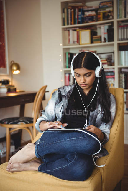 Donna che ascolta musica con cuffie e tablet digitale in salotto a casa — Foto stock