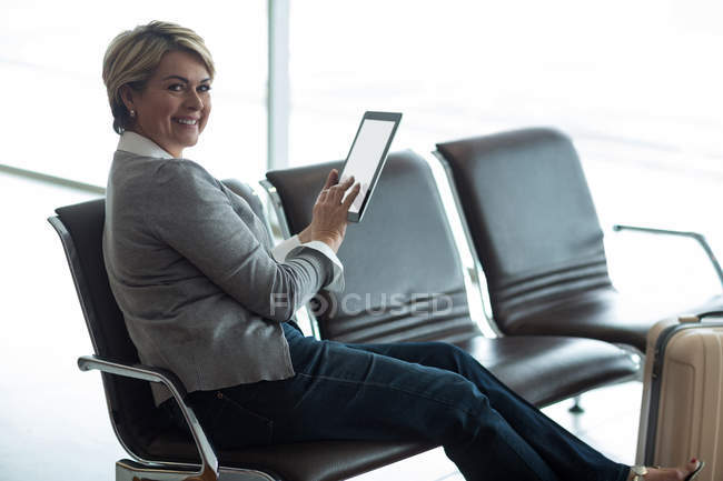Усміхаючись підприємець, використовуючи цифровий планшетний у зону очікування в аеропорту терміналу — стокове фото
