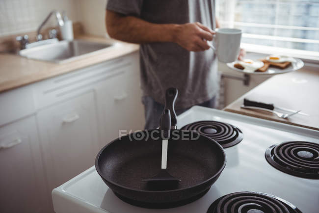 Mann in der Mitte mit Frühstücksteller und Kaffeebecher in der Küche — Stockfoto