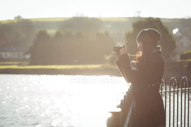 Женщина фотографирует на цифровую камеру в солнечный день в парке — стоковое фото