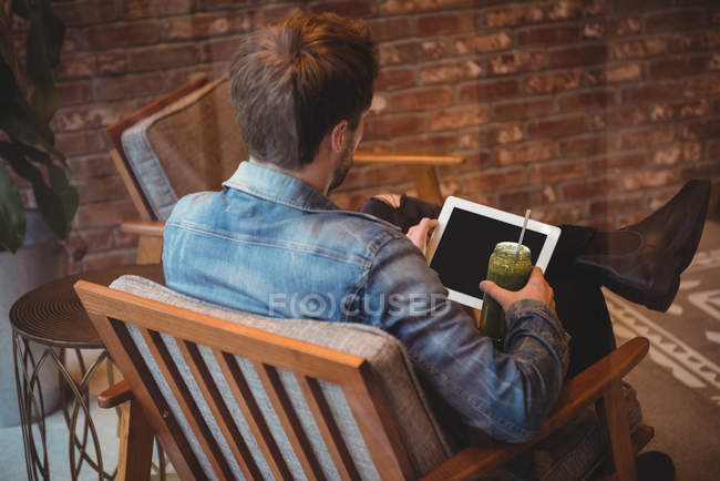 Чоловік використовує цифровий планшет, маючи сік у кафе — стокове фото