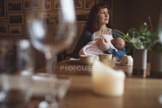 Мати тримає милу дитину в руках у кафе — стокове фото