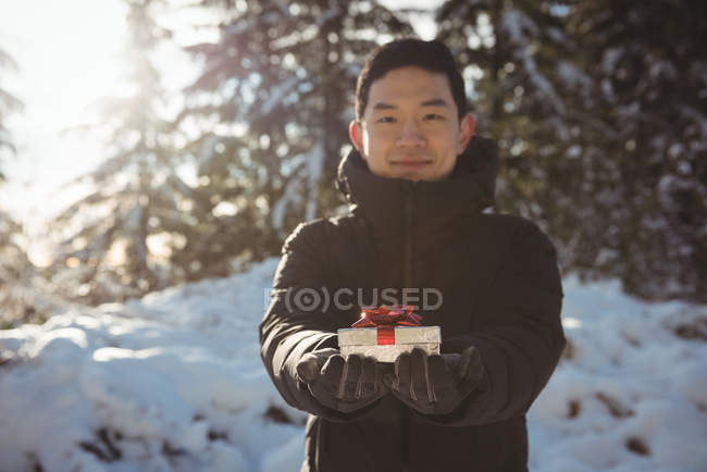 Porträt eines lächelnden Mannes, der im Winter ein Geschenk überreicht — Stockfoto