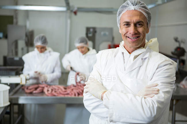 Портрет мясника, стоящего со скрещенными руками на мясокомбинате — стоковое фото