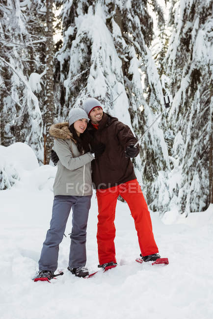 Счастливая пара лыжников делает селфи на заснеженной горе — стоковое фото