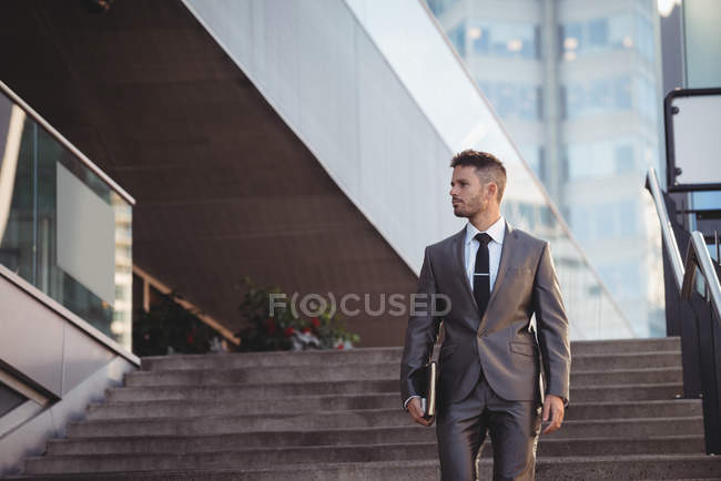 Homme d'affaires avec un journal intime marchant dans les escaliers dans le bureau — Photo de stock