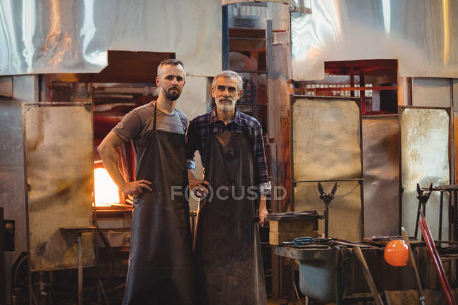 Retrato del equipo de sopladores de vidrio con brazos cruzados en fábrica de soplado de vidrio - foto de stock