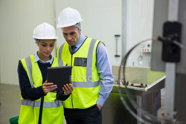 Two technicians discussing over digital tablet at meat factory — Stock Photo