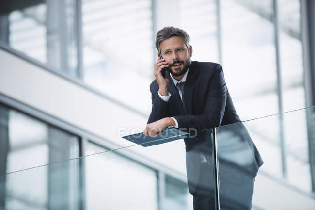 Бізнесмен розмовляє на мобільному телефоні всередині офісної будівлі — стокове фото