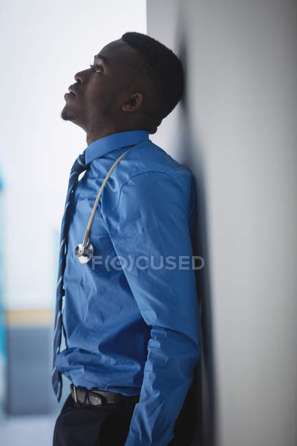 Sad doctor leaning on wall in hospital corridor — Stock Photo