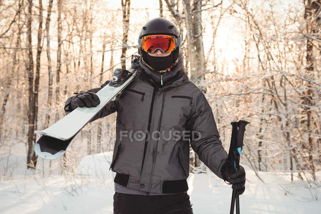 Портрет мужчины в лыжной одежде с лыжами на плече — стоковое фото