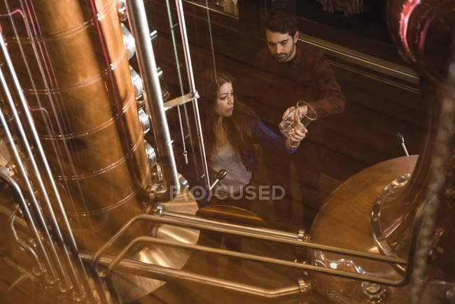 Homem e mulher examinando amostra de álcool na fábrica de cerveja — Fotografia de Stock