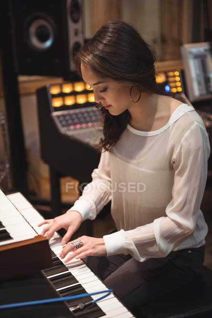 Женщина играет на пианино в музыкальной студии — стоковое фото