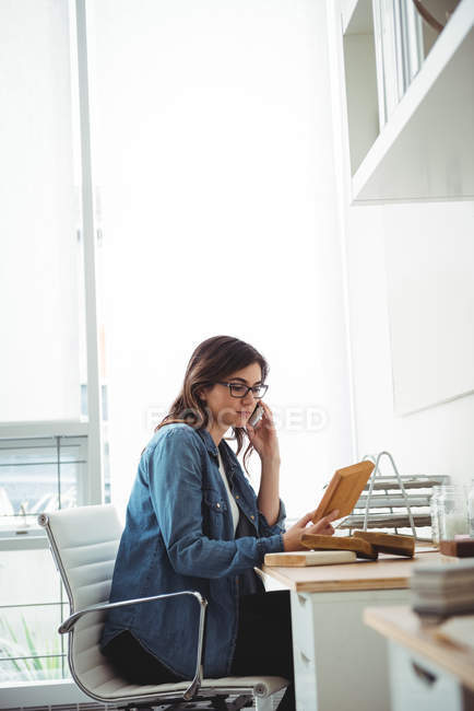 Business executive talking on mobile phone while looking at stones slab in office — Stock Photo