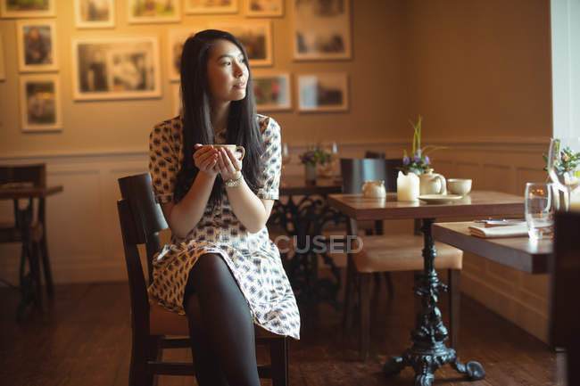 Mulher atenciosa tomando xícara de café no café — Fotografia de Stock