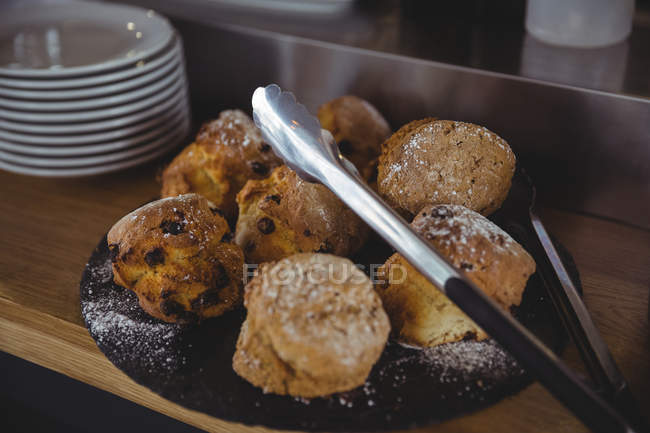Primer plano de las galletas con tong en la mesa en la cafetería - foto de stock