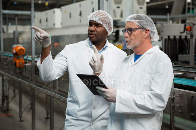 Trabajadores masculinos inspeccionando productos en fábrica de bebidas frías - foto de stock