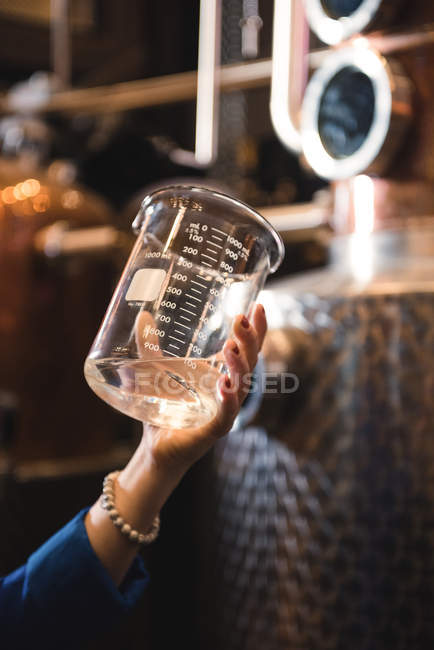 Close-up de mulher segurando um copo de medição na fábrica de cerveja — Fotografia de Stock