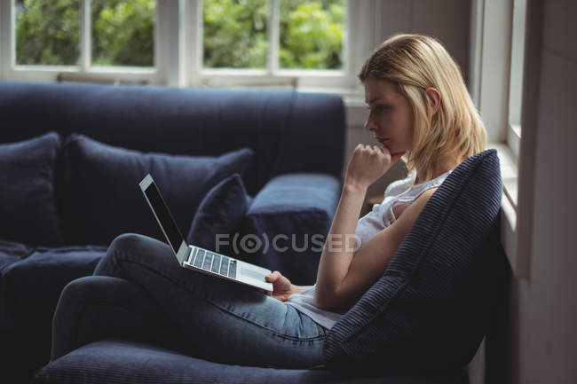 Belle femme utilisant un ordinateur portable dans le salon à la maison — Photo de stock