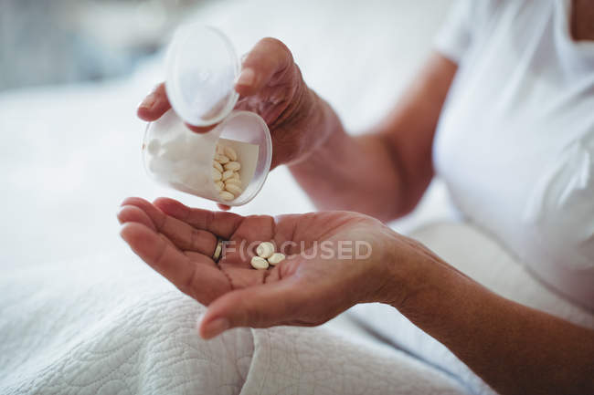 Mid section of senior woman taking medicine in bedroom at home — Stock Photo