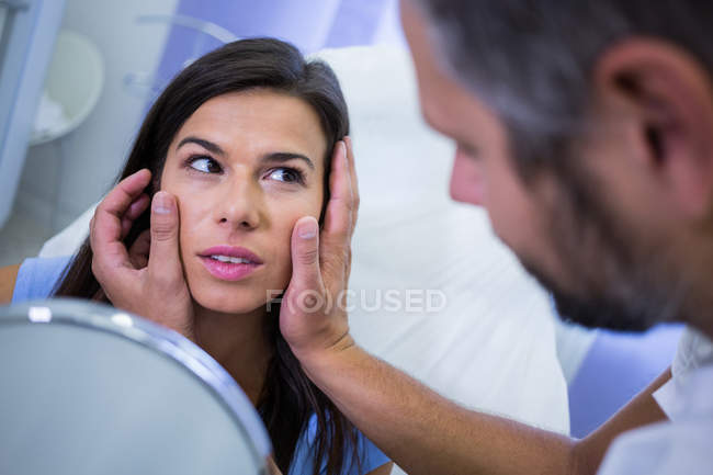 Врач проверяет кожу пациента после косметического лечения в клинике — стоковое фото