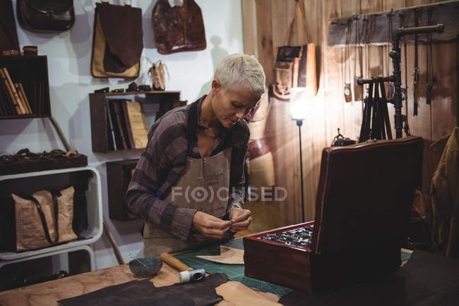 Ремесленница, работающая над куском кожи в мастерской — стоковое фото