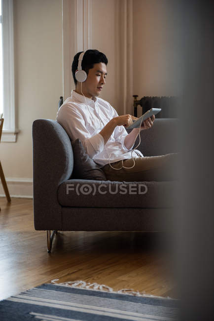 Man listening music on digital tablet at home — Stock Photo