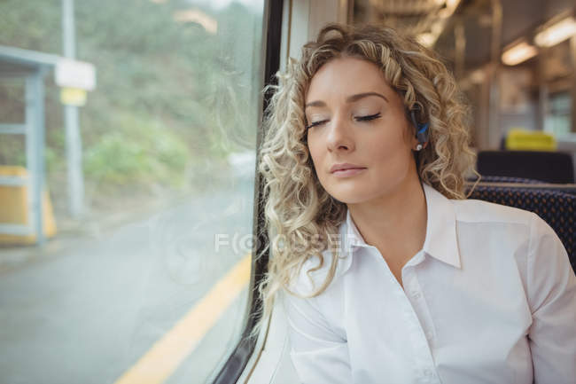 Mujer de negocios cansada durmiendo mientras viaja en tren - foto de stock
