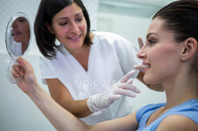 Médico examinando cara de paciente femenina en clínica - foto de stock