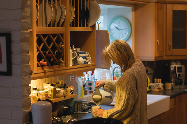 Donna che prepara il caffè in cucina a casa — Foto stock