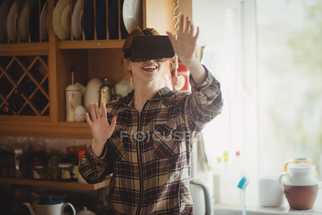 Женщина испытывает виртуальную реальность гарнитура на кухне дома — стоковое фото