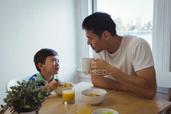 Pai e filho interagem enquanto tomam café da manhã em casa — Fotografia de Stock