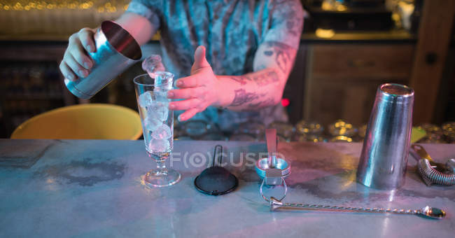 Cantinero preparando una bebida en el mostrador en el bar - foto de stock