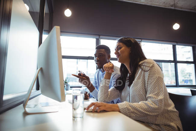 Бизнесмен и коллега работают за компьютером в офисе — стоковое фото