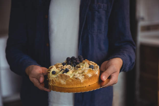 Mid section of man holding blueberry cake in living room at home — Stock Photo