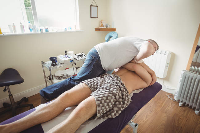 Зрелый физиотерапевт осматривает плечо пациента-мужчины в клинике — стоковое фото