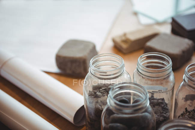 Sample of pebbles in jar on table at office — Stock Photo