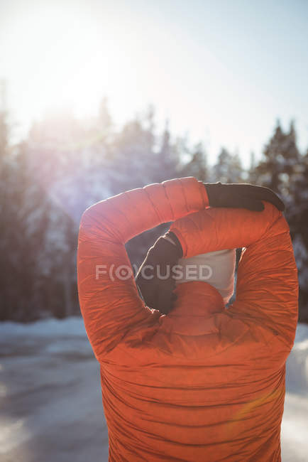Rückansicht eines Mannes, der im Winter die Arme im Wald ausstreckt — Stockfoto