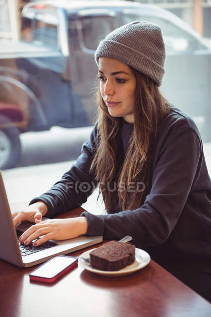 Mulher em roupas de inverno usando laptop no restaurante — Fotografia de Stock
