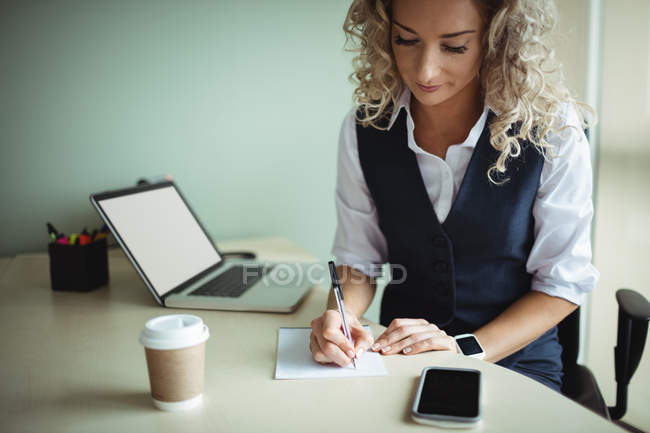 Femme d'affaires écrit sur le bloc-notes dans le bureau — Photo de stock