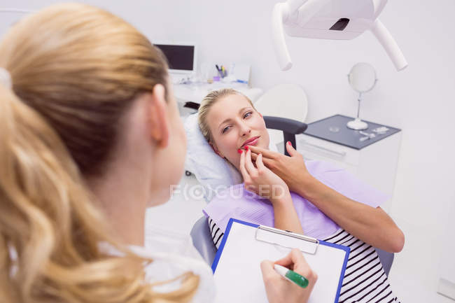 Médico conversando com paciente do sexo feminino com dor de dente na clínica — Fotografia de Stock