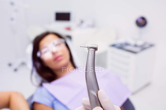 Primer plano del dentista sosteniendo la pieza de mano dental en la clínica dental - foto de stock