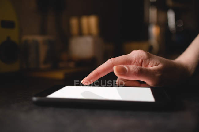 Рука жінки використовує цифровий планшет на кухні вдома — стокове фото