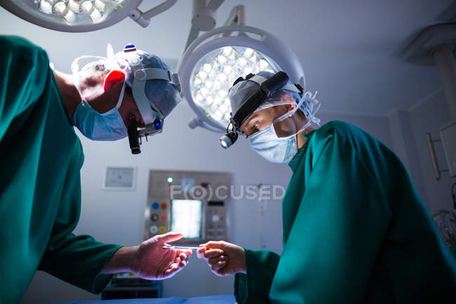 Cirurgiões vestindo lupas cirúrgicas durante a realização da operação no teatro de operação — Fotografia de Stock
