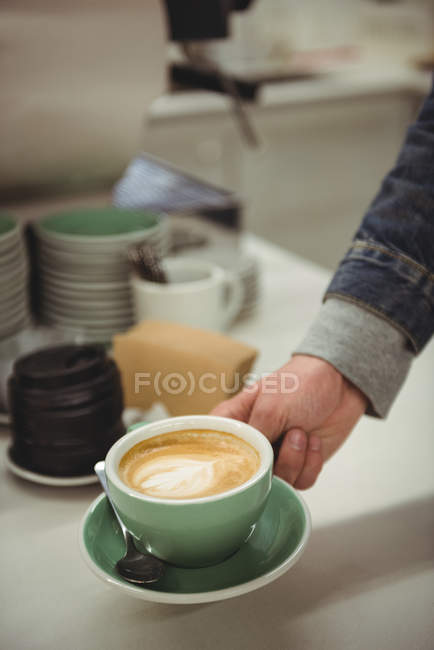 Hand picking coffee with beautiful latte art in coffee shop — Stock Photo