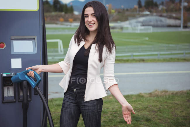 Front view of beautiful woman using plug-in electric machine on street — Stock Photo