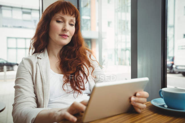 Embarazada mujer de negocios usando tableta digital en cafetería de oficina - foto de stock