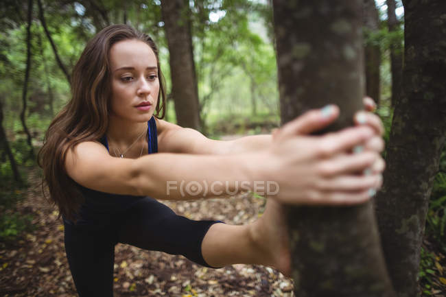 Mulher realizando ioga na floresta em um dia ensolarado — Fotografia de Stock