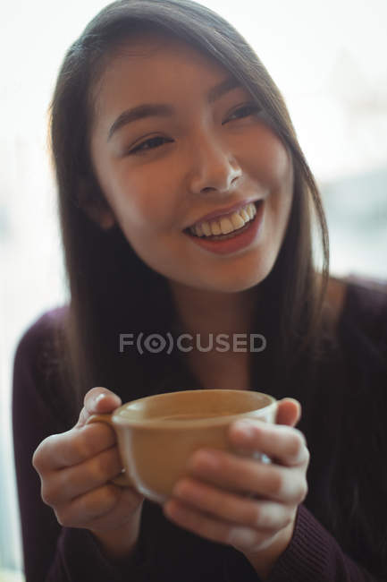 Donna sorridente che prende una tazza di caffè al caffè — Foto stock